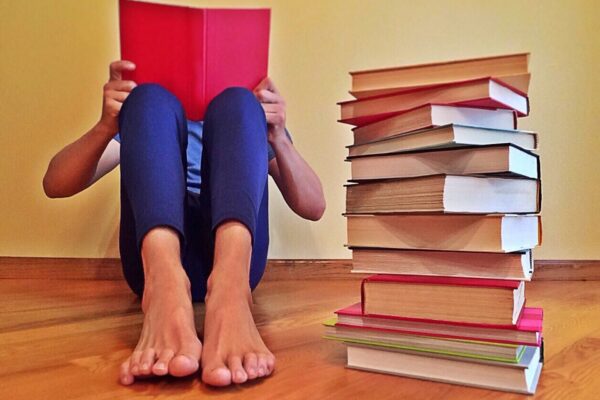 A reader sits next to a stack of books.