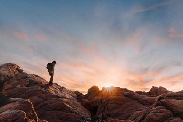 A person walking along a rocky trail at sunset.