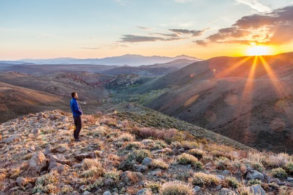 A man watching the sunrise from a mountain ridge.