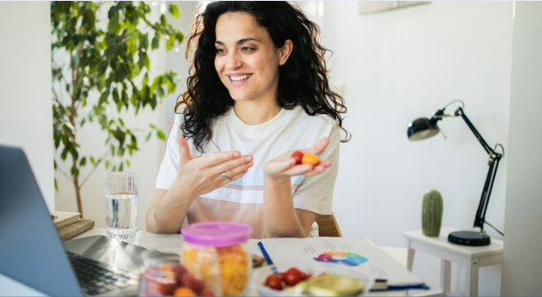 A lady eating fruit while working on her computer.