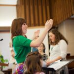 A young woman leads a choir at church.