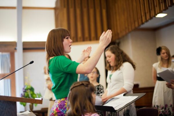 A young woman leads a choir at church.