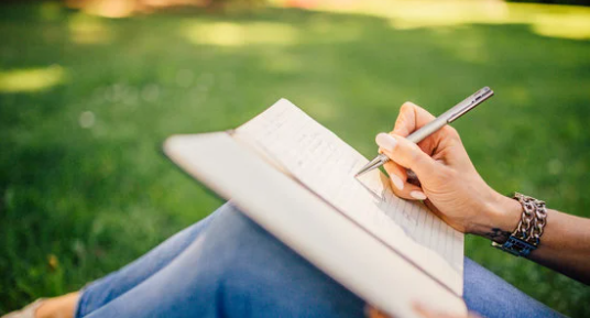 A young woman writes in a notebook.