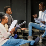 Actors gather around to study their scripts.