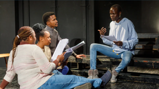 Actors gather around to study their scripts.