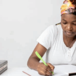 A young woman writes in a notebook.