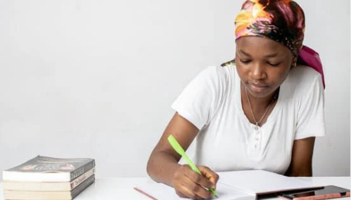 A young woman writes in a notebook.