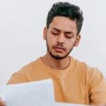 A young man studies a piece of paper intently.