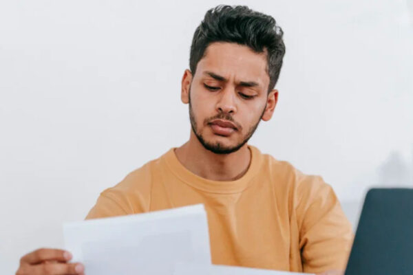 A young man studies a piece of paper intently.