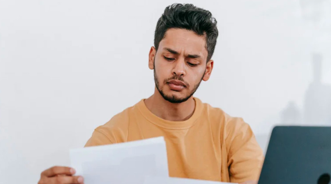 A young man studies a piece of paper intently.