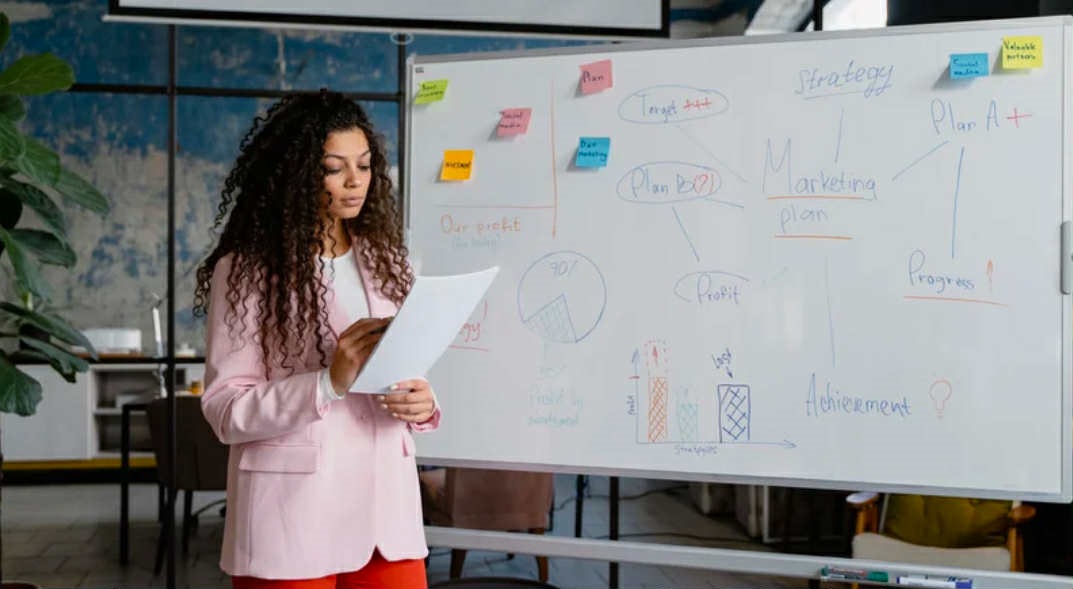 A woman standing in front of a whiteboard.