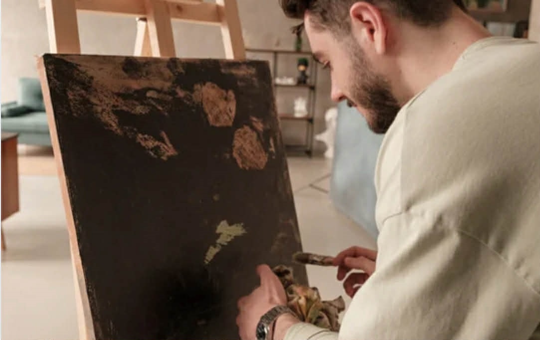 A young man paints on a canvas.