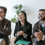 Three agents, two male, one female, applaud a pitch.