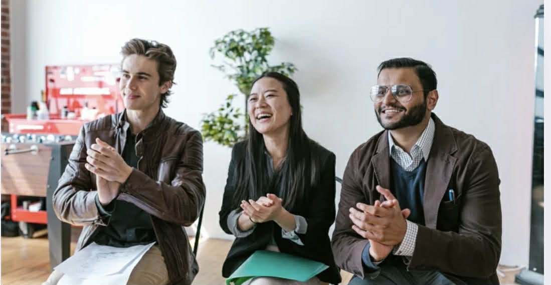 Three agents, two male, one female, applaud a pitch.