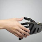 A human hand and a robotic hand reaching toward one another.
