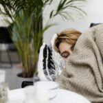 A woman sleeps on a sofa, cocooned in a blanket