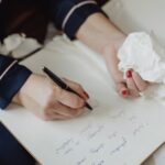 A closeup of a writer's hands, one holding a pen and the other holding a tissue.