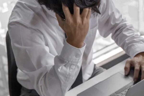 A man sitting with a desk with his head in his hands.